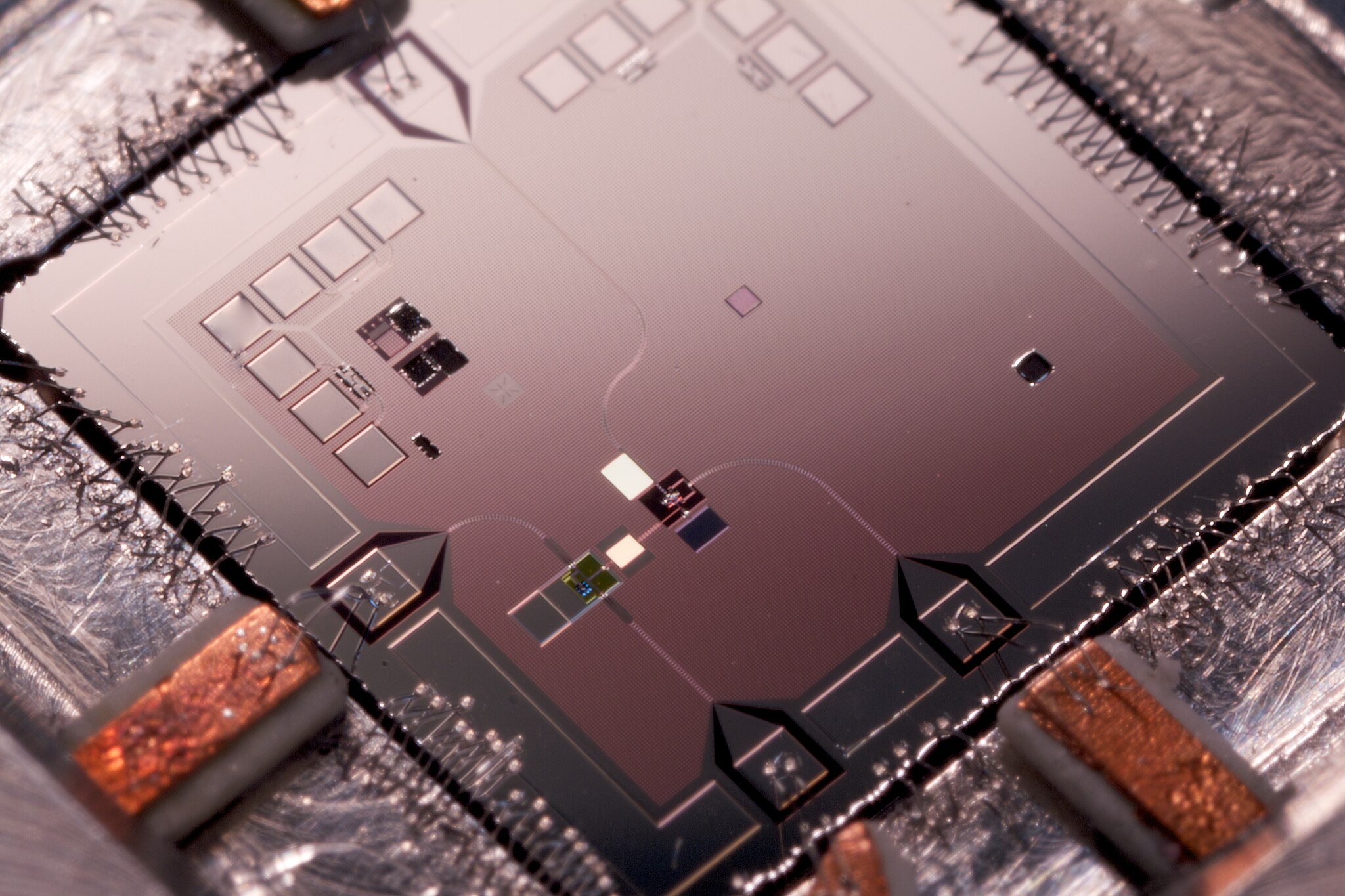 Photograph of a quantum machine. The mechanical resonator which was placed in a superposition is situated in the bottom left of the chip. The smaller white rectangle is the coupling capacitor between the mechanical resonator and the qubit.